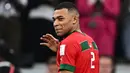 Pemain Prancis, Kylian Mbappe mengenakan baju milik pemain Maroko, Achraf Hakimi berjalan meninggalkan lapangan setelah laga semifinal Piala Dunia 2022 yang berlangsung di Al Bayt Stadium, Qatar, Rabu (14/12/2022) waktu setempat. Prancis menang dengan skor 2-0 melalui gol Theo Hernandez dan Randal Kolo Muani. (AFP/Gabriel Bouys)