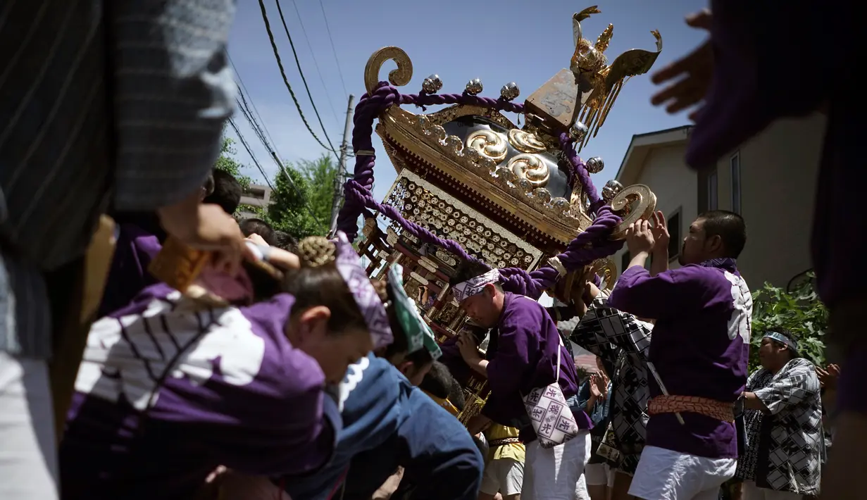 Mikoshi atau tempat suci portabel diayunkan para peserta saat festival Tenno-sai di Kuil Susanoo di Tokyo, Jepang (3/6). Dalam ritual ini, selain upacara di kuil Shinto, mereka juga membawa mikoshi ke jalan-jalan sekitar. (AP Photo / Eugene Hoshiko)