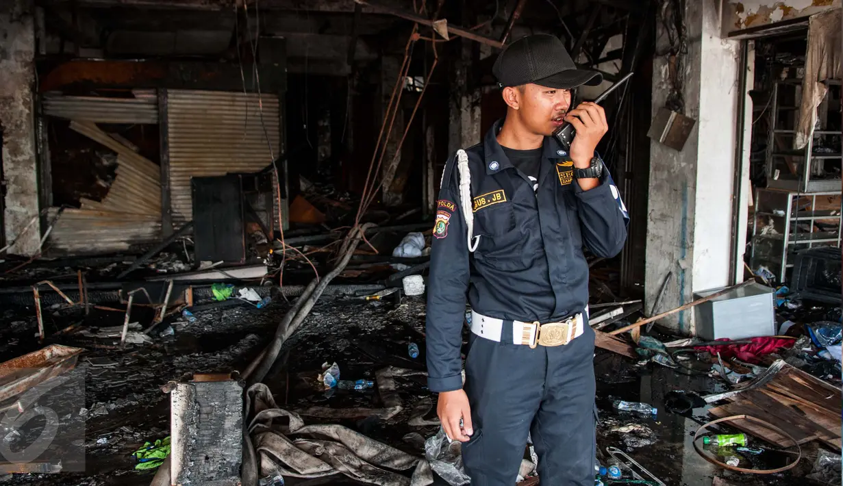 Seorang satpam mengecek keadaan kios usai terbakar di Pasar Senen, Jakarta, Jumat (20/1). Badan Penanggulangan Bencana Daerah DKI Jakarta menyatakan jumlah kios Pasar Senen sebanyak 1.691 kios. (Liputan6.com/Gempur M Surya)