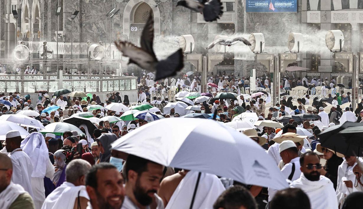 Para jamaah Muslim berjalan di sepanjang kompleks Masjidil Haram di bawah kipas kabut air yang dipasang di kota suci Mekah pada Minggu 24 Mei 2026, menjelang ibadah haji tahunan. (Zain JAAFAR/AFP)