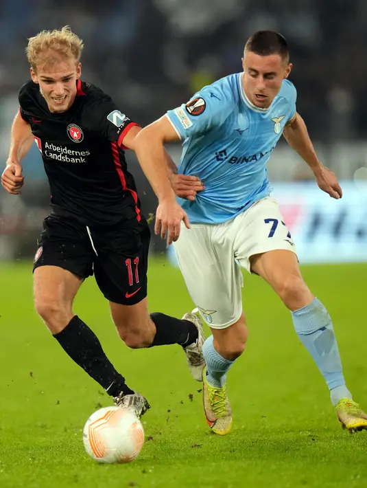 Pemain FC Midtjylland Gustav Isaksen (kiri) berebut bola dengan pemain Lazio Adam Marusic pada pertandingan sepak bola Grup F Liga Europa di Stadion Olimpiade Roma, Italia, 27 Oktober 2022. Lazio menang 2-1 atas FC Midtjylland. (AP Photo/Alessandra Tarantino)