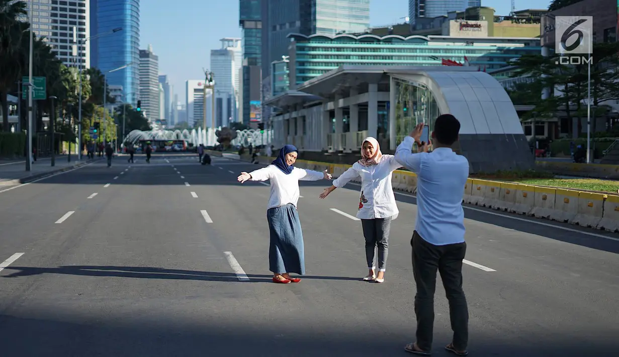 Dua orang wanita berfoto dengan latar belakang Jalan MH Thamrin yang masih ditutup oleh aparat keamanan di Jakarta, Jumat (24/5/2019). Ditutupnya Jalan MH Thamrin terkait unjuk rasa menolak hasil Pemilu 2019 dimanfaatkan sebagian warga untuk berfoto. (Liputan6.com/Immanuel Antonius)