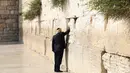 Presiden AS Donald Trump memasukkan sebuah catatan di antara bebatuan Tembok Ratapan, tempat suci milik kaum Yahudi, di Yerusalem, Senin (22/5). Donald Trump menjadi Presiden AS pertama yang berdoa di Tembok Ratapan. (AP Photo/Evan Vucci)