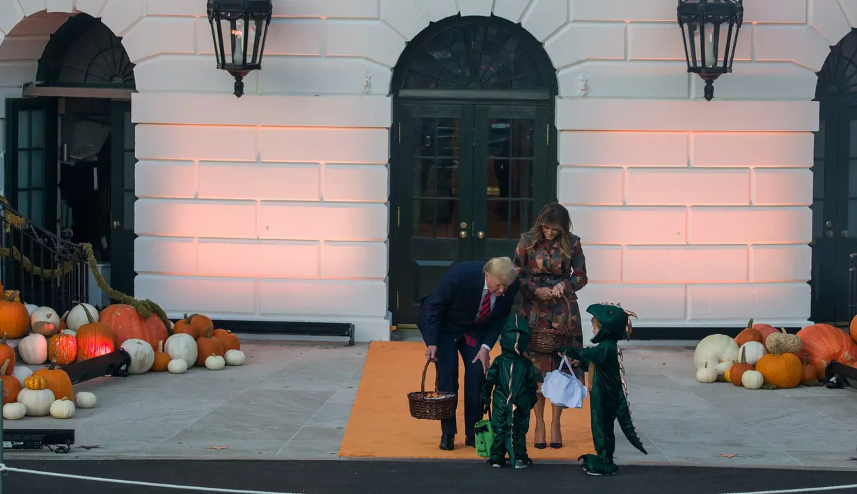 Presiden AS, Donald Trump dan ibu negara Melania Trump membagikan permen kepada anak-anak selama acara trick-or-treat Halloween di South Lawn, Gedung Putih, Senin (28/10/2019). Ini adalah tradisi kepresidenan Amerika untuk merayakan hari besar sambil membuat open house. (AP/Alex Brandon)