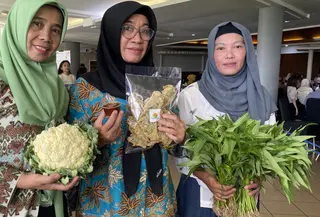 Nunung (kiri), Ivon (tengah), dan Nengsih (kanan), memegang sayur hasil panen dari kebun mereka dalam acara pameran Bibit ka Jati bagian dari kegiatan Urban Features di Bumi Sangkuriang, Bandung, Selasa, 10 Februari 2026. (Liputan6.com/Dikdik Ripaldi)