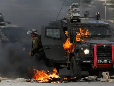 Tentara Israel meninggalkan kendaraan yang terbakar oleh lemparan bom molotov warga Palestina di pinggiran Kota Ramallah, Tepi Barat, Rabu (27/3). Bentrokan ini sebagai bentuk protes terhadap tahanan Palestina yang berada di Israel. (AP Photo/Majdi Mohammed)