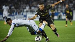 Pemain Paris Saint-Germain (PSG), Kylian Mbappe, berebut bola dengan pemain AJ Auxerre, Rayan Raveloson, pada laga Liga Prancis, di Stade de I’Abbe Deschamps, Senin (22/5/2023). PSG menang dengan skor tipis 2-1. (AFP/Julien De Rosa)