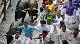 Ribuan orang yang membawa syal merah berlari menghindari serudukan dari banteng-banteng yang sengaja dilepas di Festival San Fermin di Pamplona, Spanyol (10/07/2014) (AFP PHOTO/Ander GILLENEA)