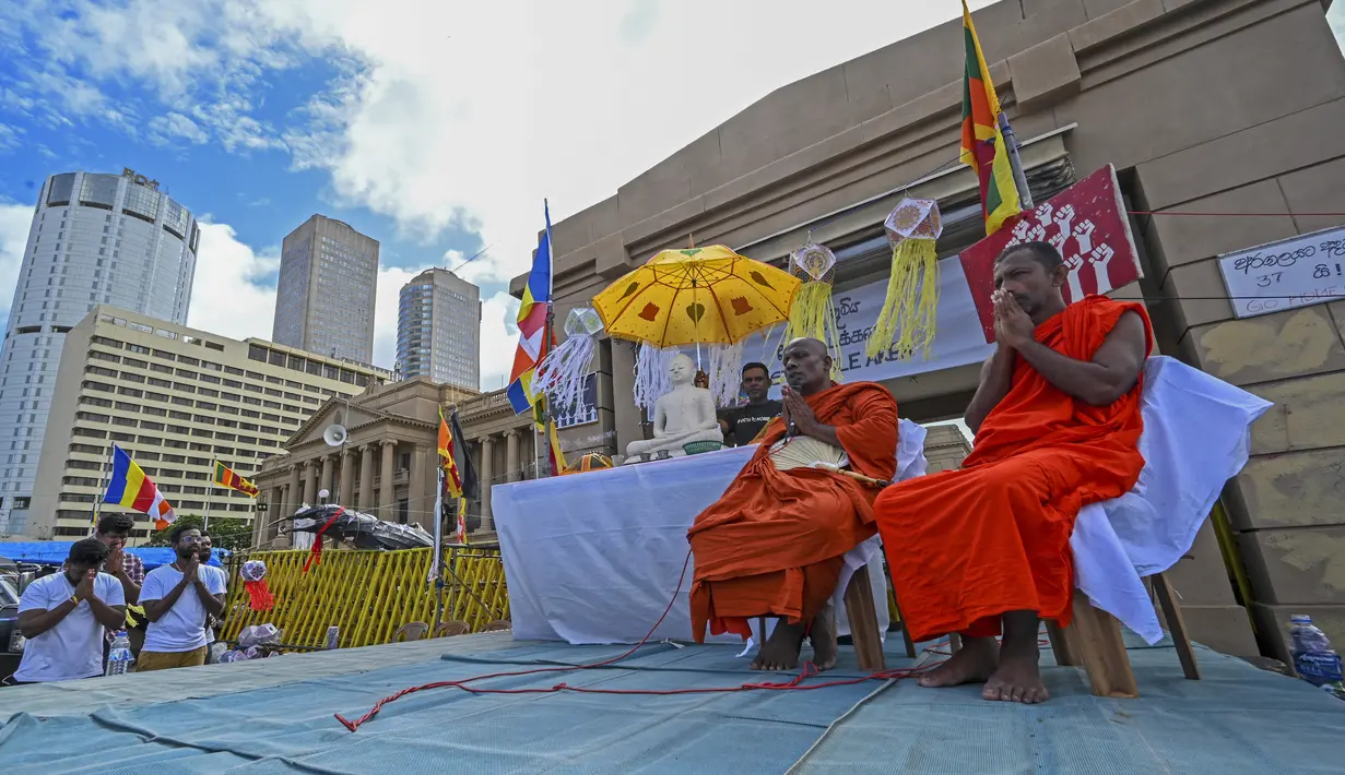 <p>Biksu Buddha dan demonstran anti-pemerintah berdoa selama festival Waisak di dekat kantor Presiden di Kolombo, Sri Lanka, Minggu (15/5/2022). Pihak berwenang Sri Lanka mencabut jam malam nasional pada 15 Mei ketika negara pulau yang kekurangan uang tersebut bersiap untuk merayakan festival Buddha yang penting, dengan perayaan yang diredam oleh krisis keuangan yang semakin memburuk. (Ishara S. KODIKARA / AFP)</p>