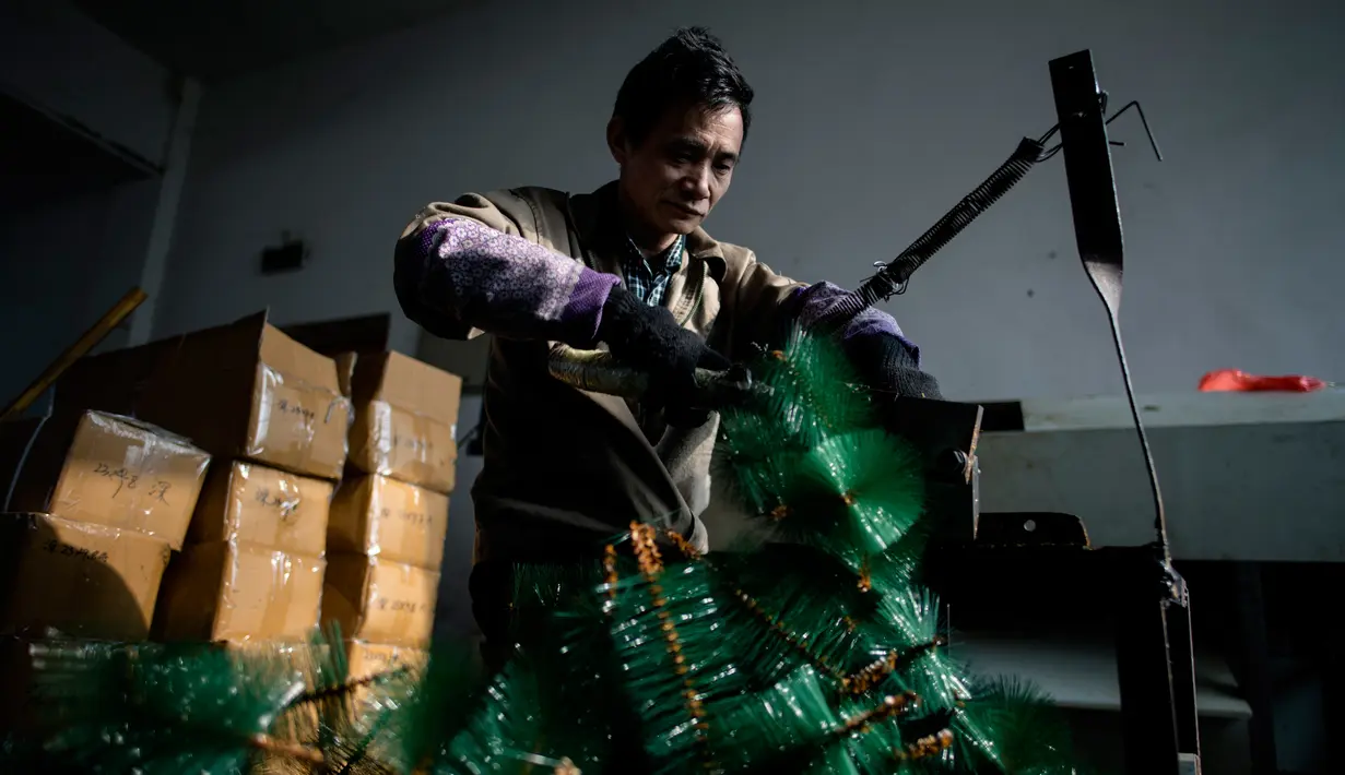 Seorang pekerja menyelesaikan pembuatan pohon Natal di pabrik Sun Xudan, Yiwu, China (7/12). Sun Xudan adalah pabrik terbesar di China yang memproduksi berbagai aksesoris Natal, termasuk pohon cemara buatan. (AFP Photo/Johannes Eisele)
