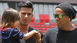 Eks Striker Barcelona, Ronaldinho menyapa gadis kecil sebelum pertandingan persahabatan melawan mantan pemain Kosta Rika di Stadion Nasional di San Jose, (4/8). (AFP Photo/Ezequiel Becerra)