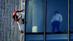 Alain Robert yang dikenal sebagai 'Spiderman Prancis' (kiri) memanjat gedung pencakar langit Skyper di pusat Frankfurt, Jerman, 23 November 2021. Alain Robert memanjat gedung setinggi 153 meter itu untuk meningkatkan kesadaran dunia tentang masalah perubahan iklim. (AP Photo/Michael Probst)