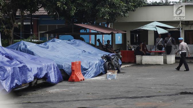 Terpal menutupi sejumlah mobil yang dirusak di Polsek Ciracas, Jakarta, Rabu (12/12). Selain mobil, bangunan Polsek Ciracas juga ikut dirusak massa. (Liputan6.com/Herman Zakharia)