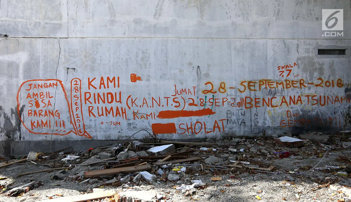 Tulisan cat oranye dengan pesan Kami Rindu Rumah Kami dan Jangan Ambil Sisa Barang Kamis menghiasi dinding rumah pasca gempa bumi dan tsunami di Jalan Trans Sulawesi, Palu, Sulawesi Tengah, Kamis (4/10). (Liputan6.com/Fery Pradolo)