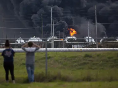 Warga mengamati kebakaran pabrik TPC Group yang meledak di Port Neches, Texas (27/11/2019). Dua ledakan besar 13 jam terpisah membakar pabrik kimia dan menyebabkan tiga pekerja terluka. (Marie D. De Jesús/Houston Chronicle via AP)