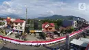 Pelajar SMA membentangkan bendera Merah Putih sepanjang 2,3 kilometer di Jalan Panjaitan dan Jalan Nani Wartabone, Gorontalo, Kamis (23/1/2020). Acara tersebut dilakukan untuk mengenang 78 tahun Hari Patriotik. (Liputan6.com/Arfandi Ibrahim)