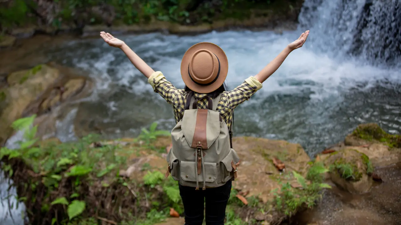 Seorang perempuan sedang menikmati keindahan alam air terjun (Foto Dok: Freepik/freepik)
