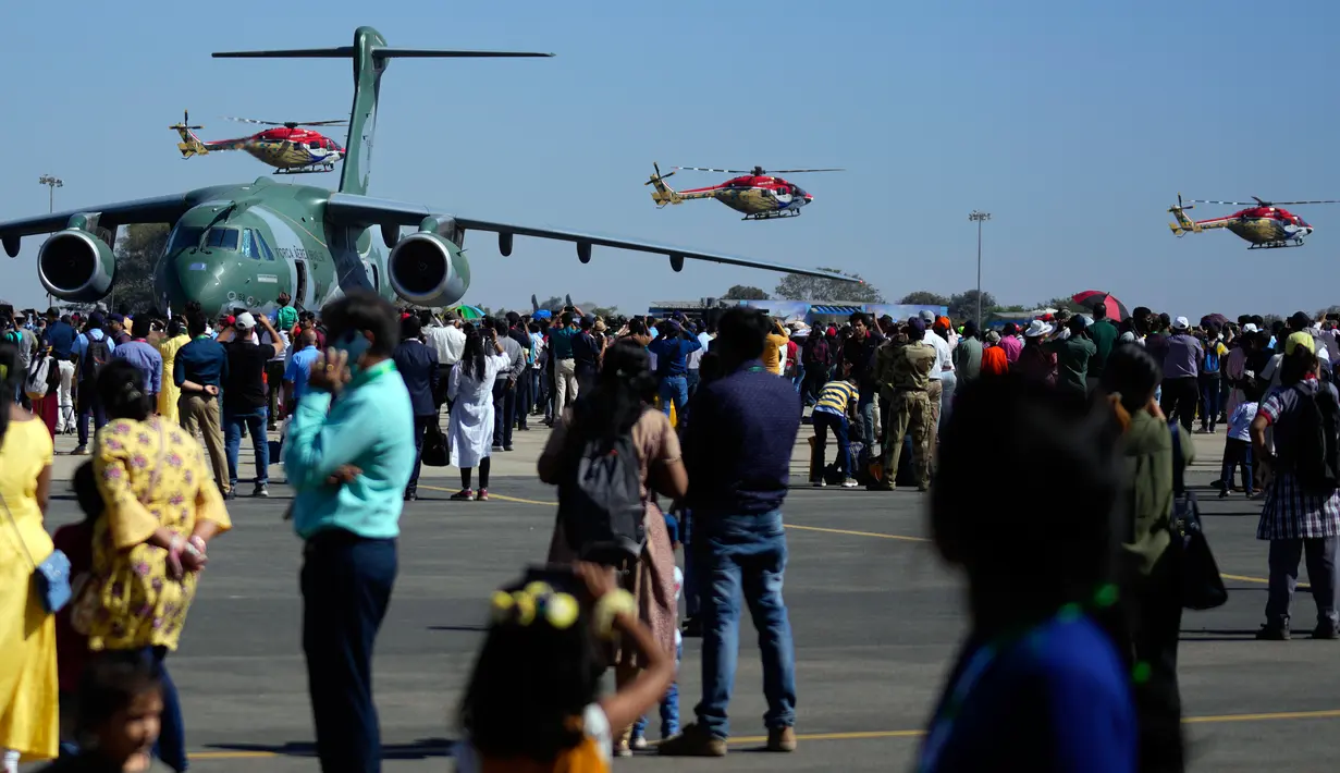 Tim aerobatik Angkatan Udara India, Sarang, terbang dalam formasi melewati Embraer C-390 Millennium Angkatan Udara Brasil pada hari keempat Aero India 2023 di pangkalan udara Yelahanka, Bengaluru, India, 16 Februari 2023. Aero India adalah acara dua tahunan dengan demonstrasi terbang oleh tim stunt dan militer serta komersial paviliun tempat perusahaan penerbangan memamerkan produk dan teknologinya. (AP Photo/Aijaz Rahi)