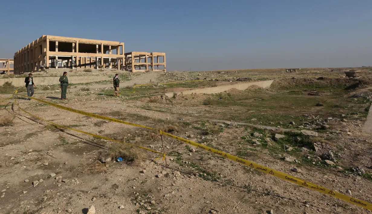 Pasukan Kurdi berdiri di sekitar kuburan massal yang diduga lokasi makam anggota Yazidi Irak di pinggiran kota Sinjar, 30 November 2015. Pasukan Kurdi menemukan kuburan ini usai berhasil merebut kembali kota Irak dari militan ISIS. (Reuters/Ari Jalal)