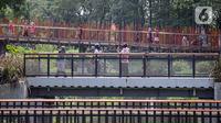 Pengunjung berfoto di jembatan Tebet Eco Park, Jakarta, Selasa (10/5/2022). Warga memanfaatkan libur dengan bermain dan berolahraga di taman terbuka setelah pemerintah memperpanjang masa liburan sekolah hingga tanggal 11 Mei 2022. (Liputan6.com/Faizal Fanani)