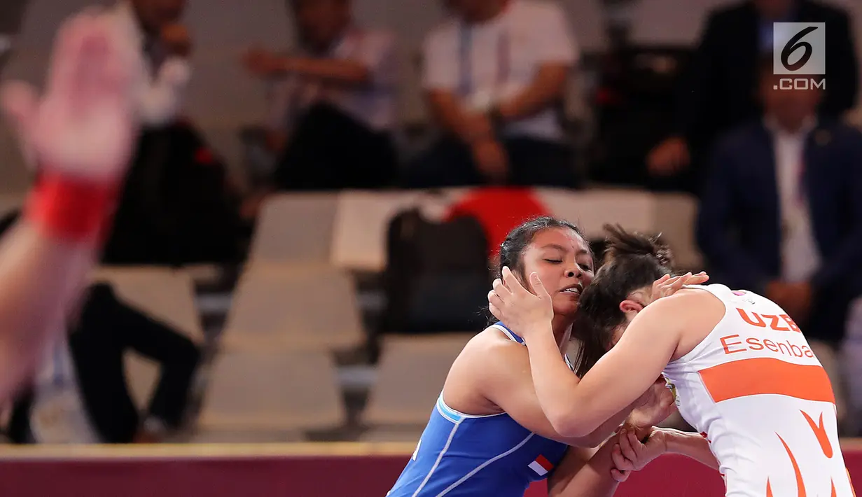 Pegulat Indonesia, Ayuningtias Mutiara (kiri) bertarung dengan pegulat Uzbekistan, Esenbaeva Nabira pada babak perdelapan final 57 kg putri dalam Asian Games 2018 di JCC Senayan, Senin (20/8). Ayuningtias kalah dengan skor 0-7. (Liputan6.com/Fery Pradolo)