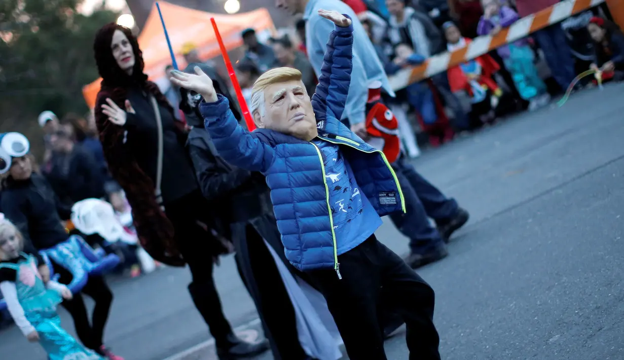 Seorang anak laki-laki memakai topeng calon presiden dari Partai Republik, Donald Trump saat acara tahunan Parade Nyack Halloween di Desa Nyack, New York, AS (29/10). (Reuters/Mike Segar)