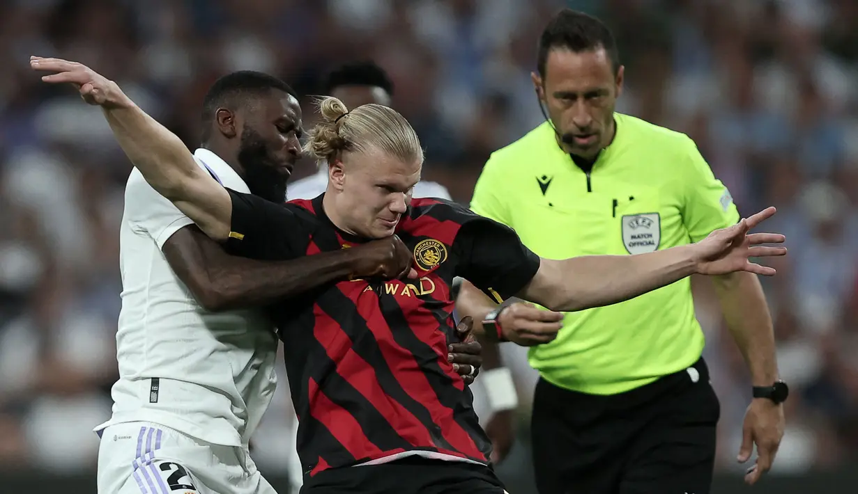 Pemain Manchester City, Erling Haaland (tengah) berebut bola dengan pemain Real Madrid, Antonio Rudiger pada laga leg pertama semifinal Liga Champions 2022/2023 di Santiago Bernabeu, Madrid, Rabu (10/05/2023) WIB. Laga berakhir dengan skor 1-1. (AFP/Oscar Del Pozo)