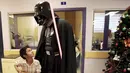 Seorang cosplayer berpakaian Darth Vader berbincang dengan seorang anak saat acara amal oleh El Salvador Star Wars fan club di Rumah Sakit Benjamin Bloom Anak Nasional di San Salvador, El Salvador (14/12). (REUTERS/Jose Cabezas)