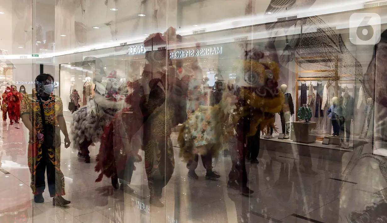 Refleksi atraksi barongsai terlihat dari jendela salah satu gerai di Senayan City mall, Jakarta, Jumat (12/2/2021). Atraksi Barongsai yang digelar dengan berkeliling pusat perbelanjaan tersebut untuk menghibur pengunjung sekaligus untuk menyambut Tahun Baru Imlek 2572. (Liputan6.com/Johan Tallo)