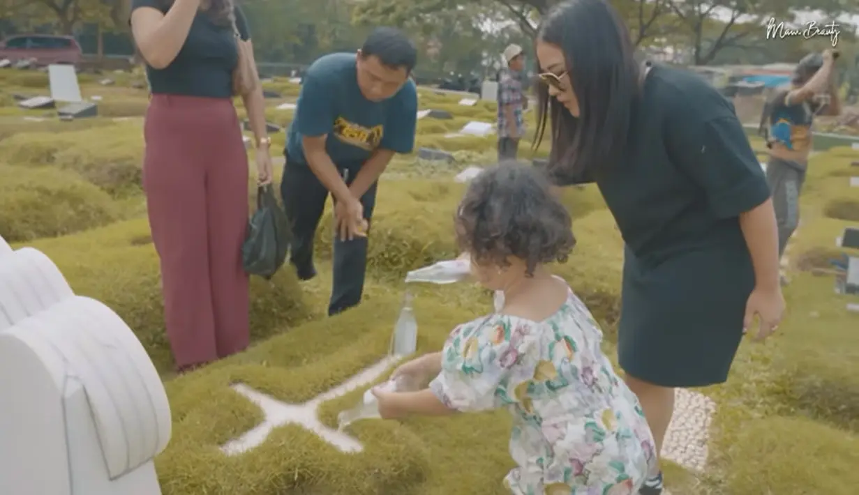 Setelah menancapkan bunga yang dibawa, Gewa juga menaburkan bunga hingga menyiram air mawar di atas makam Glenn. [Youtube/Mutia Ayu]