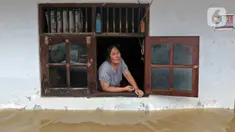 Warga melihat keluar jendela saat banjir di RW 07, Kelurahan Pekayon, Jakarta Timur, Sabtu (20/2/2021). Banjir di kawasan tersebut terjadi akibat curah hujan yang tinggi. (Liputan6.com/Herman Zakharia)