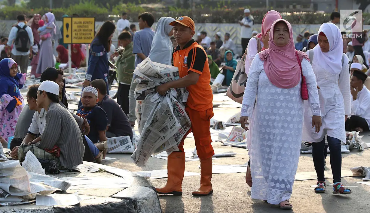 Petugas membersihkan koran usai salat id Hari Raya Idul Fitri 1 Syawal 1439 H di kawasan Senen, Jakarta, Jumat (15/6). Banyaknya koran yang berserakan membuat petugas harus sigap membersihkan agar tidak mengotori jalan. (Liputan6.com/Immanuel Antonius)