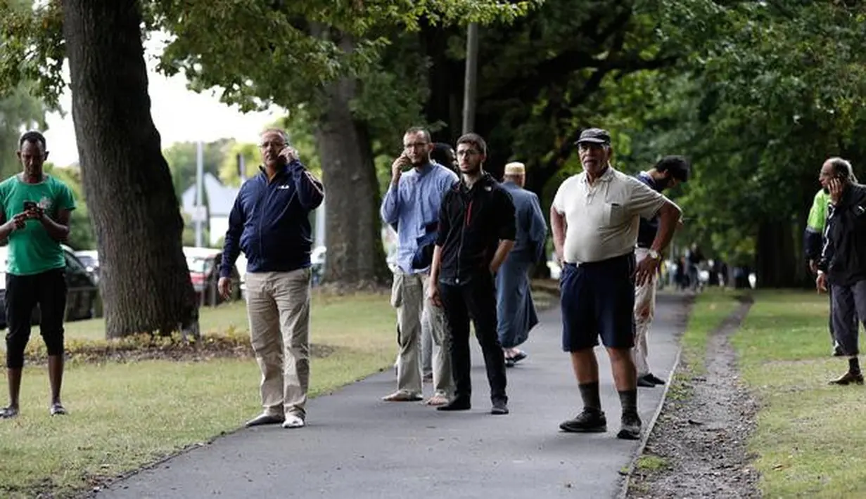 Warga menunggu dekat lokasi penembakan di Masjid Al Noor, Christchurch, Selandia Baru, Jumat (15/3). Polisi masih menyisir lokasi kejadian dan mengosokan seluruh ruas jalan Deans Avenue. (AP Photo/Mark Baker)