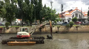 Pekerja menggunakan alat berat untuk mengeruk lumpur dan sampah yang mengendap di anak Sungai Ciliwung, Jakarta, Jumat (26/1). Pengerukan dilakukan untuk mencegah pendangkalan sungai. (Liputan6.com/Immanuel Antonius)