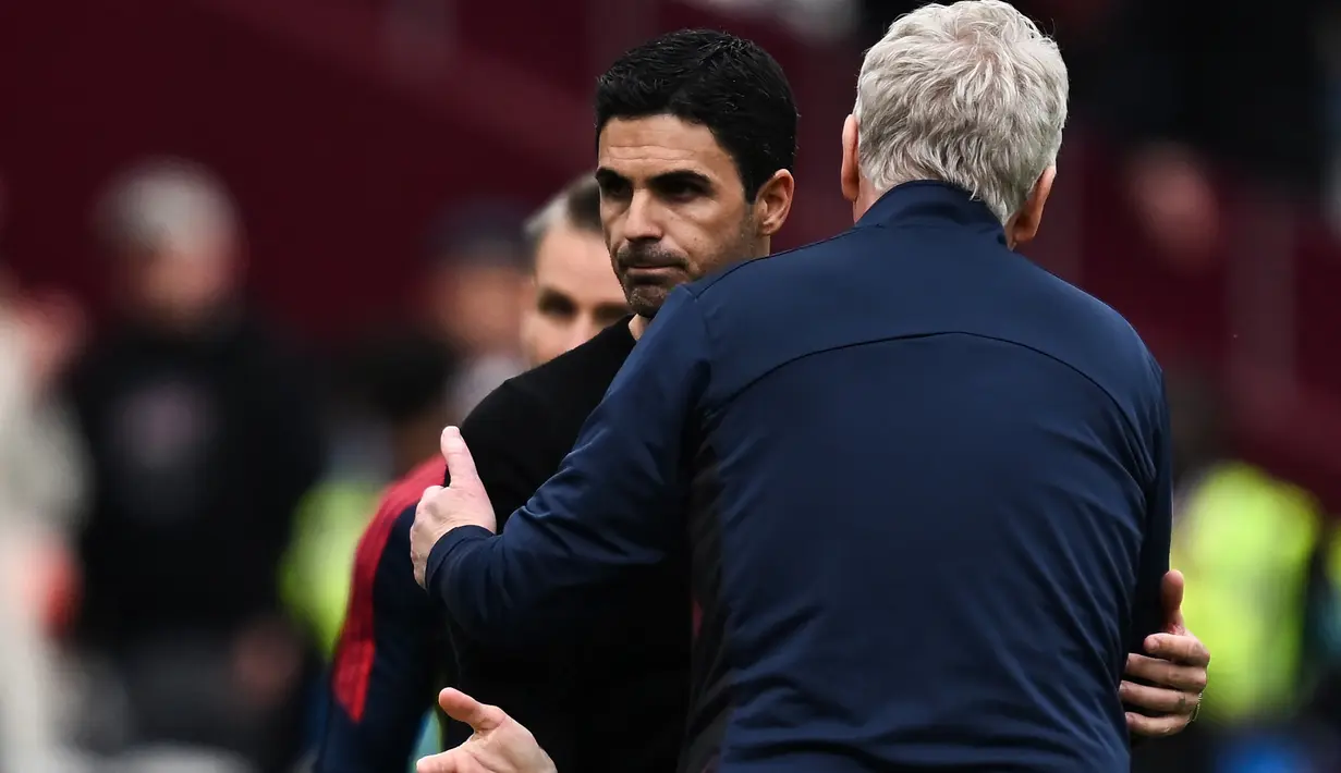 Ekspresi kecewa pelatih Arsenal, Mikel Arteta saat berpelukan dengan pelatih West Ham United, David Moyes setelah berakhirnya laga pekan ke-31 Liga Inggris 2022/2023 di London Stadium, London (17/4/2023). (AFP/Ben Stansall)