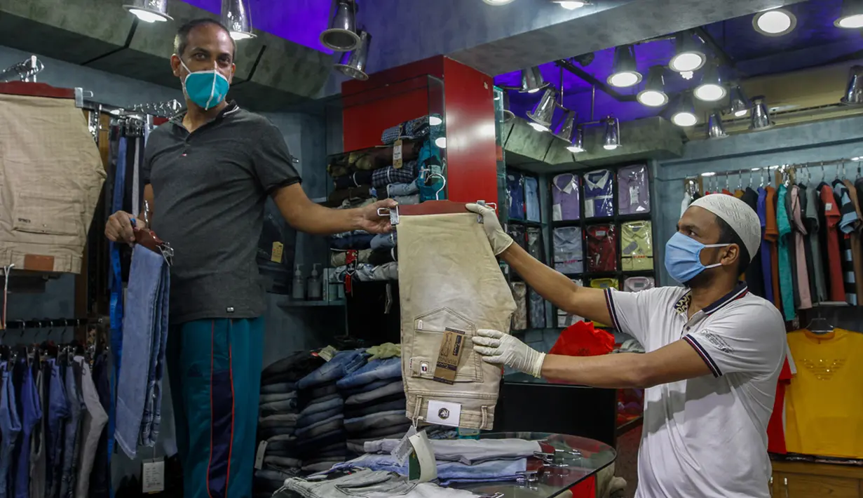 Seorang pria memilih celana di sebuah toko di pasar yang kembali dibuka, Dhaka, Bangladesh, Senin (11/5/2020). Jalan-jalan utama Dhaka kembali ramai sehari setelah toko-toko dan pasar kembali dibuka secara terbatas mengikuti aturan pemerintah. (Xinhua/Stringer)
