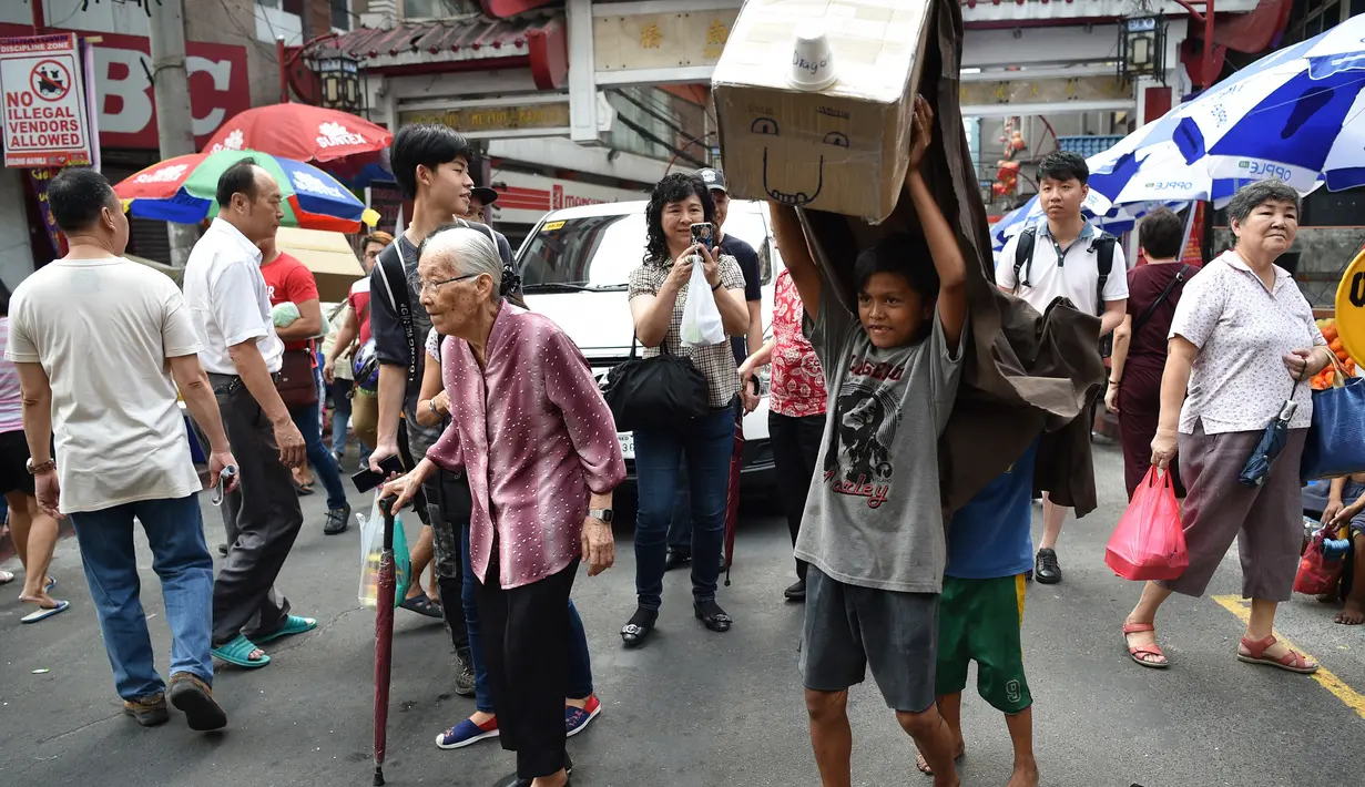Anak-anak melakukan tarian singa dengan kepala singa yang terbuat dari kardus saat menghibur pejalan kaki untuk menyambut Tahun Baru Imlek di Manila (4/2). Aksi anak-anak jalanan ini menjadi pusat perhatian warga. (AFP Photo/Ted Aljibe)