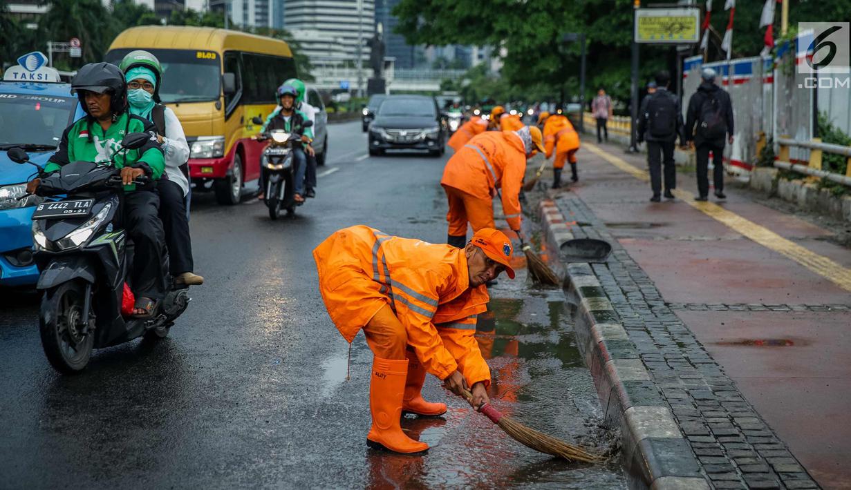 Petugas Dinas Kebersihan membersihkan genangan air usai hujan di kawasan jalan Sudirman, Jakarta, Rabu (22/11). Buruknya sistem drainase membuat petugas membersihkan genangan setiap kali hujan, meski dengan peralatan seadanya. (Liputan6.com/Faizal Fanani)