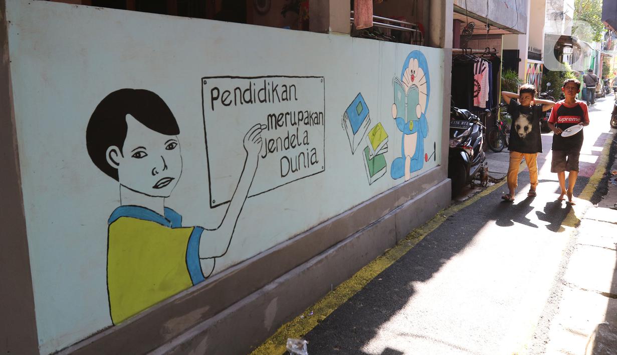 Anak-anak melintasi mural di Kampung Budaya Kawasan Jakarta Barat, Selasa (19/11/2019). Penataan dilakukan mulai daari pembenahan jalan, pembuatan resapan air, bangku, mural, hingga ubin pemandu untuk penyandang disabilitas dengan anggaran mencapai Rp2.5 miliar. (Liputan6.com/Herman Zakharia)