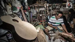 Soedarmadi yang akrab disapa Bone menyelesaikan pembuatan gitar di workshop Bone's Costum Guitar, Jakarta, Rabu (10/3/2021). Untuk mencukupi kebutuhan sehari-hari, ayah dari 4 anak ini mencari sampingan dengan membuka ternak cupang hias sembari menunggu pelanggan gitar. (merdeka.com/Iqbal S Nugroho)