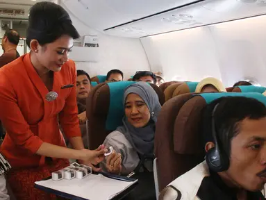 Pramugari membagikan cokelat kepada penumpang dalam penerbangan di Pesawat Garuda Indonesia menuju, Padang, Sumatera Barat, Jumat (21/4). Dalam rangka menyambut Hari Kartini, penerbangan Garuda Indonesia diawaki oleh perempuan. (Liputan6.com/Angga Yuniar)