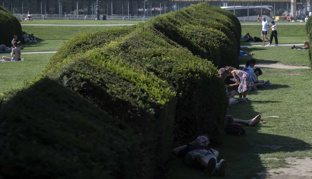 Para pejalan kaki berbaring di bawah naungan Jardin du Carrousel di Paris, Prancis pada 11 Agustus 2025, di tengah gelombang panas yang melanda Eropa. (Martin LELIEVRE/AFP)