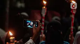 Warga mengambil foto saat mengikuti pawai obor menyambut Ramadan di kawasan Matraman Dalam, Jakarta, Minggu (27/3/2022). Pawai obor tersebut juga digelar untuk meningkatkan silaturahmi dan ukhuwah sesama umat Muslim serta menyemarakkan syiar Islam di Ibu Kota. (Liputan6.com/Faizal Fanani)
