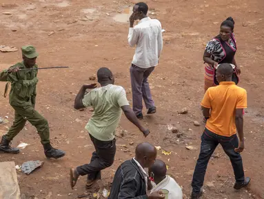 Aparat kepolisian memukuli pria saat membubarkan orang-orang yang masih berkeliaran di Kampala, Uganda (26/3/2020). Presiden Uganda Yoweri Museveni mengimbau masyarakatnya untuk tinggal di rumah selama 32 hari setelah 14 kasus positif Covid-19 teridentifikasi di negara tersebut. (AFP/Badru Katumba)