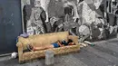 Seorang wanita tidur di sofa yang dibuang di trotoar samping mural lukisan "Guernica" karya Pablo Picasso di lingkungan Padre Carlos Mugica, Buenos Aires, Argentina, Kamis (14/12/2023). Pemerintah Argentina memotong subsidi transportasi dan energi serta mendevaluasi peso sebesar 50 persen sebagai bagian dari tindakan mengejutkan yang menurut Presiden Javier Milei diperlukan untuk menghadapi keadaan darurat ekonomi. (AP Photo/Rodrigo Abd)