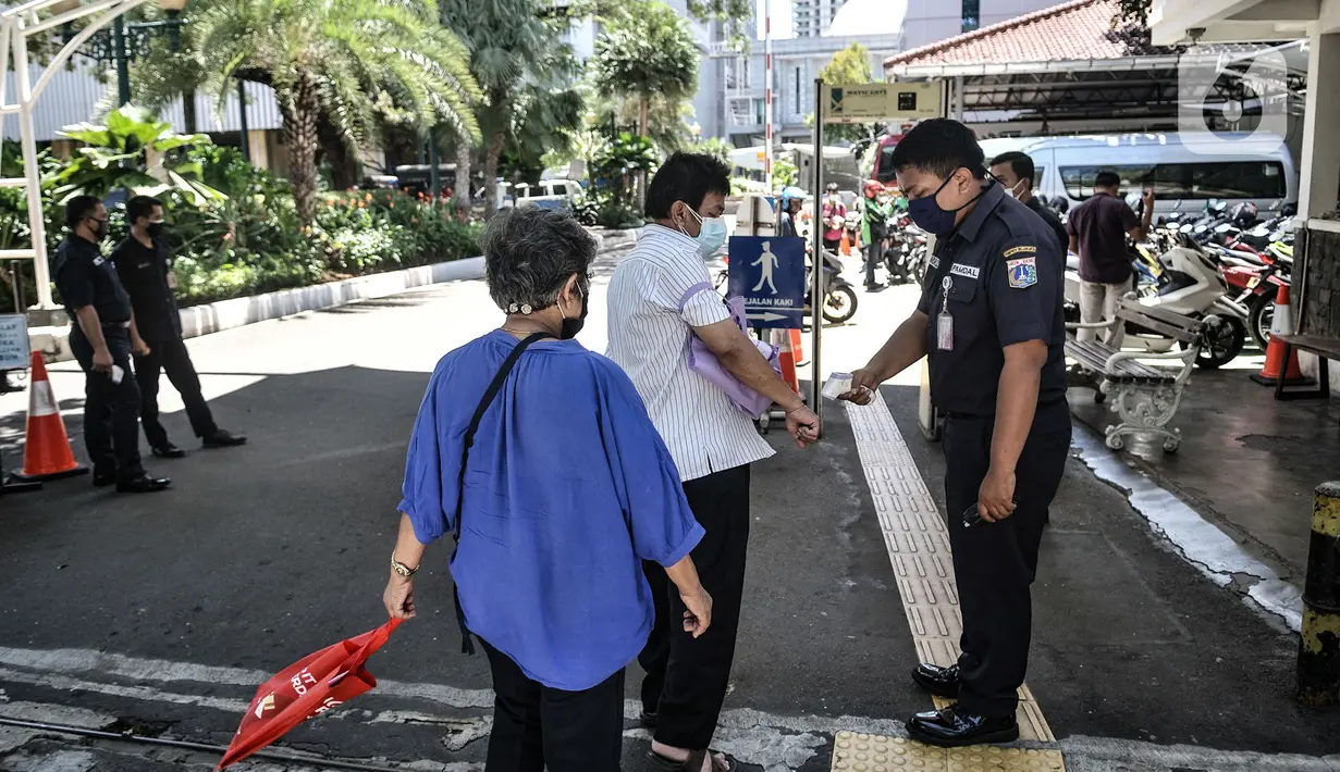 Petugas memeriksa suhu tubuh pengunjung sebelum memasuki area Balai Kota, Jakarta, Selasa (1/12/2020). Sementara itu Gedung Utama Balai Kota yang terpisah dengan Kantor Gubernur Anies tetap beroperasi dengan menerapkan protokol kesehatan. (merdeka.com/Iqbal S. Nugroho)