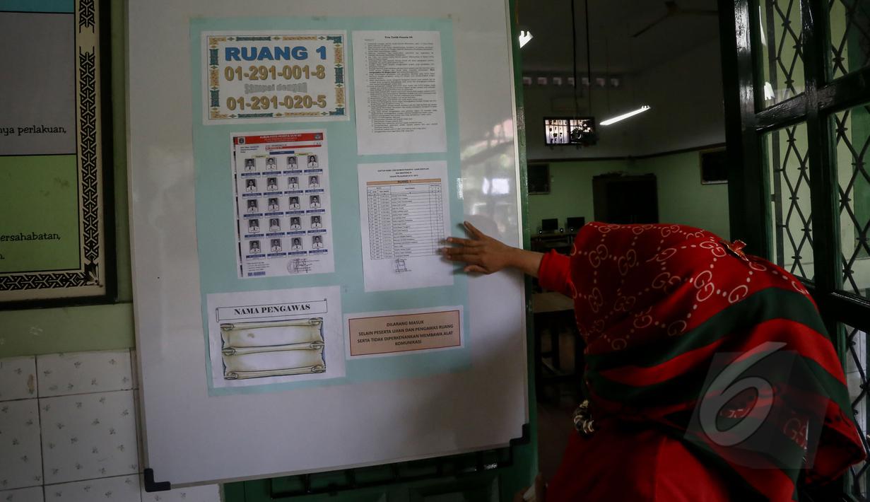 Seorang guru mempersiapkan nomor peserta siswa untuk Ujian Nasional (UN) di SDN 01 Menteng, Jakarta, Minggu (17/5/2015). Pelaksanaan UN SD akan dilakukan pada 18-20 Mei mendatang. (Liputan6.com/Faizal Fanani)
