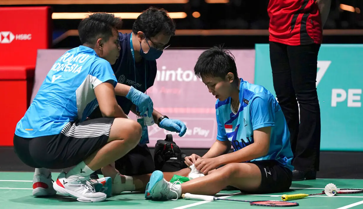 Siti Fadia Silva Ramadhanti (kanan) menerima perawatan medis disaksikan Apriyani Rahayu saat memutuskan mundur melawan China Chen Qing Chen dan Jia Yi Fan pada pertandingan semifinal ganda putri turnamen bulu tangkis Malaysia Open 2023 di Bukit Jalil Axiata Arena, Kuala Lumpur, Malaysia, Sabtu (14/1/2023). Apriyani Rahayu/Siti Fadia Silva Ramadhanti gagal mengamankan tiket final Malaysia Open 2023 setelah sepakat untuk mengakhiri laga lebih dulu karena Fadia mengalami cedera. (AP Photo/Kien Huo)