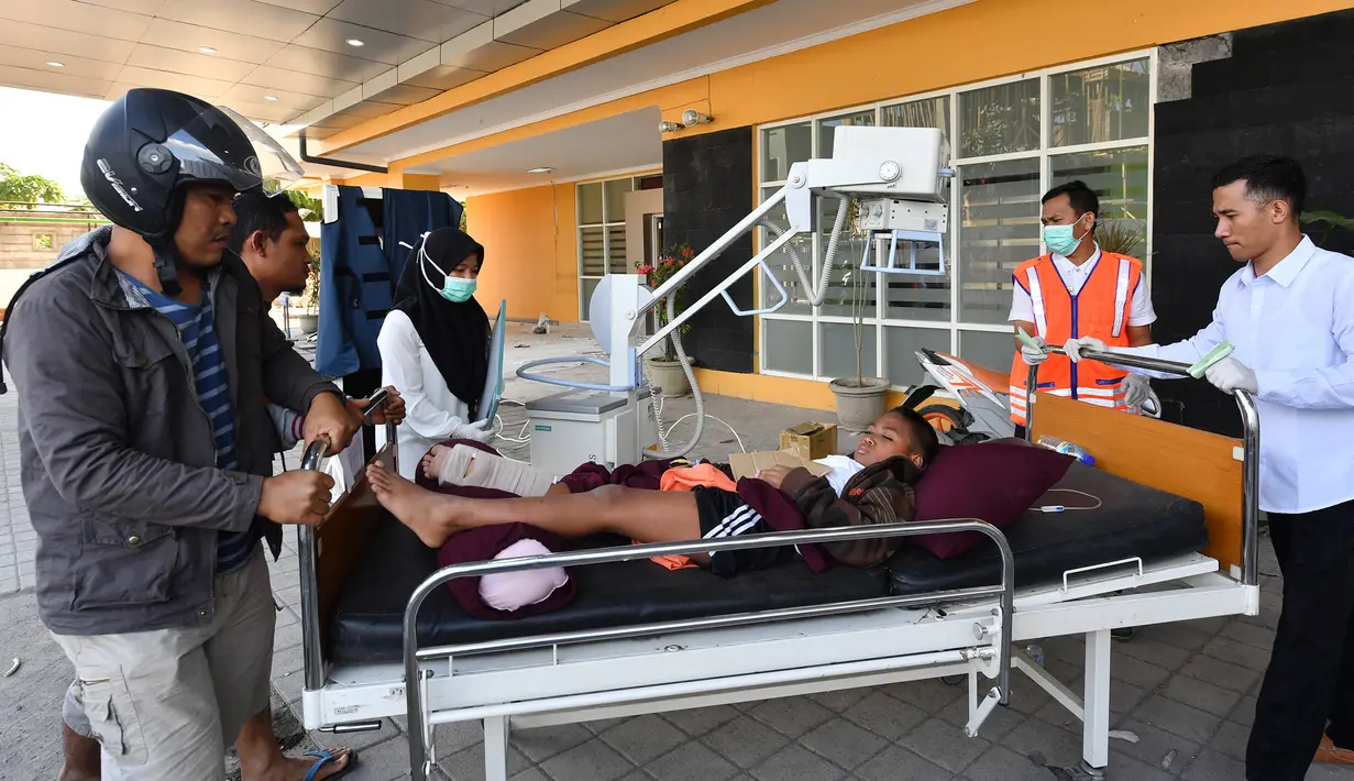 Seorang anak korban gempa Lombok mendapat perawatan medis di luar Rumah sakit Moh. Ruslan di Mataram,  Senin (6/8). Berdasarkan laporan sementara yang diterima BPBD NTB, korban meninggal akibat gempa Lombok sudah mencapai 89 orang. (AFP/ADEK BERRY)