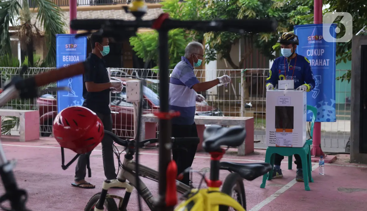 Warga bersiap memasukkan surat suara usai mencoblos dalam Pilkada 2020 di TPS 23 Pondok Jagung Timur, Tangerang Selatan, Rabu (9/12/2020). TPS Pilkada Tangerang Selatan (Tangsel) itu menggunakan tema hobi dimana petugasnya mengenakan pakaian untuk bersepeda. (Liputan6.com/Angga Yuniar)